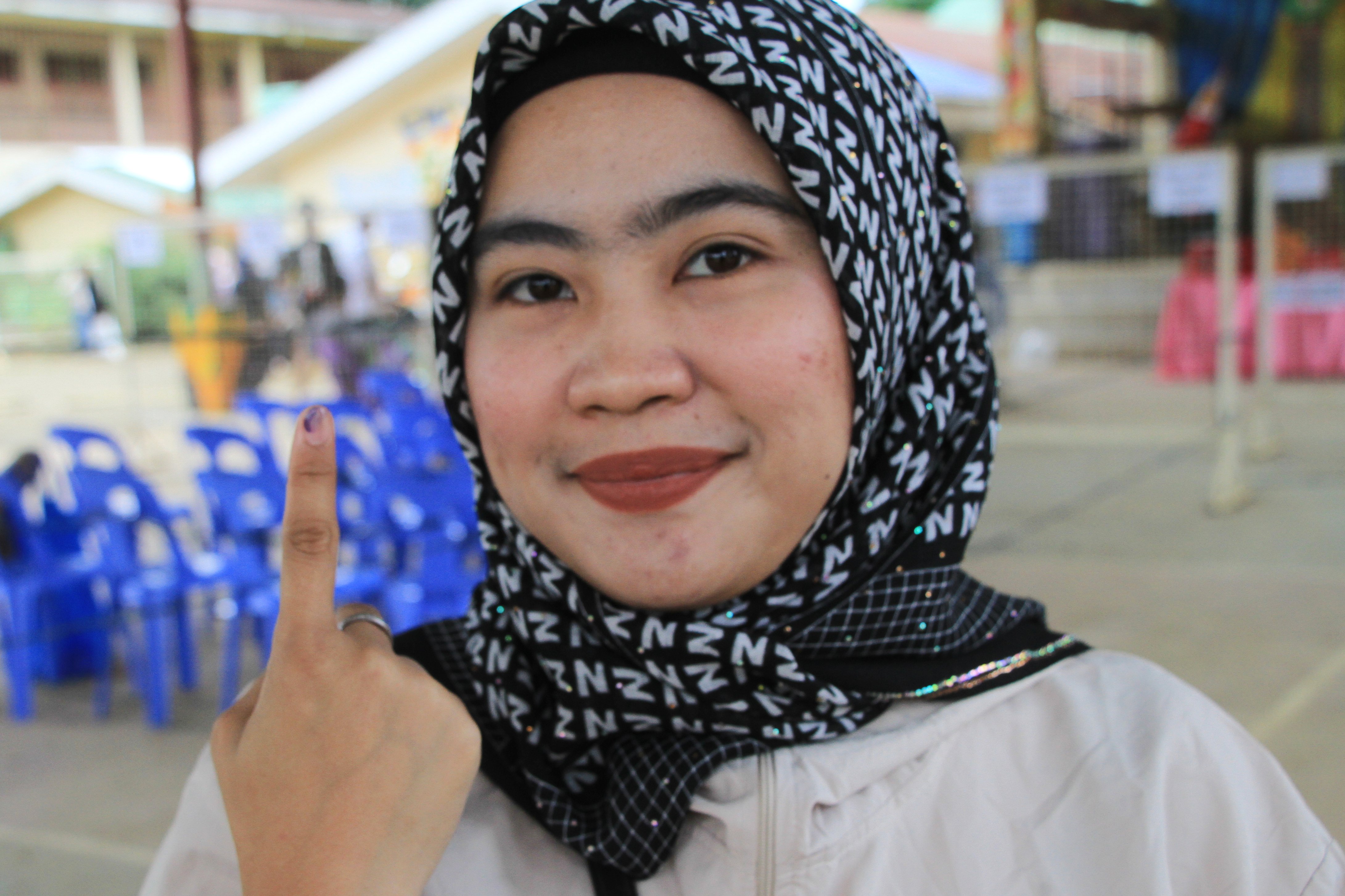 A Muslim woman voter shows the indelible ink on her fingers after voting