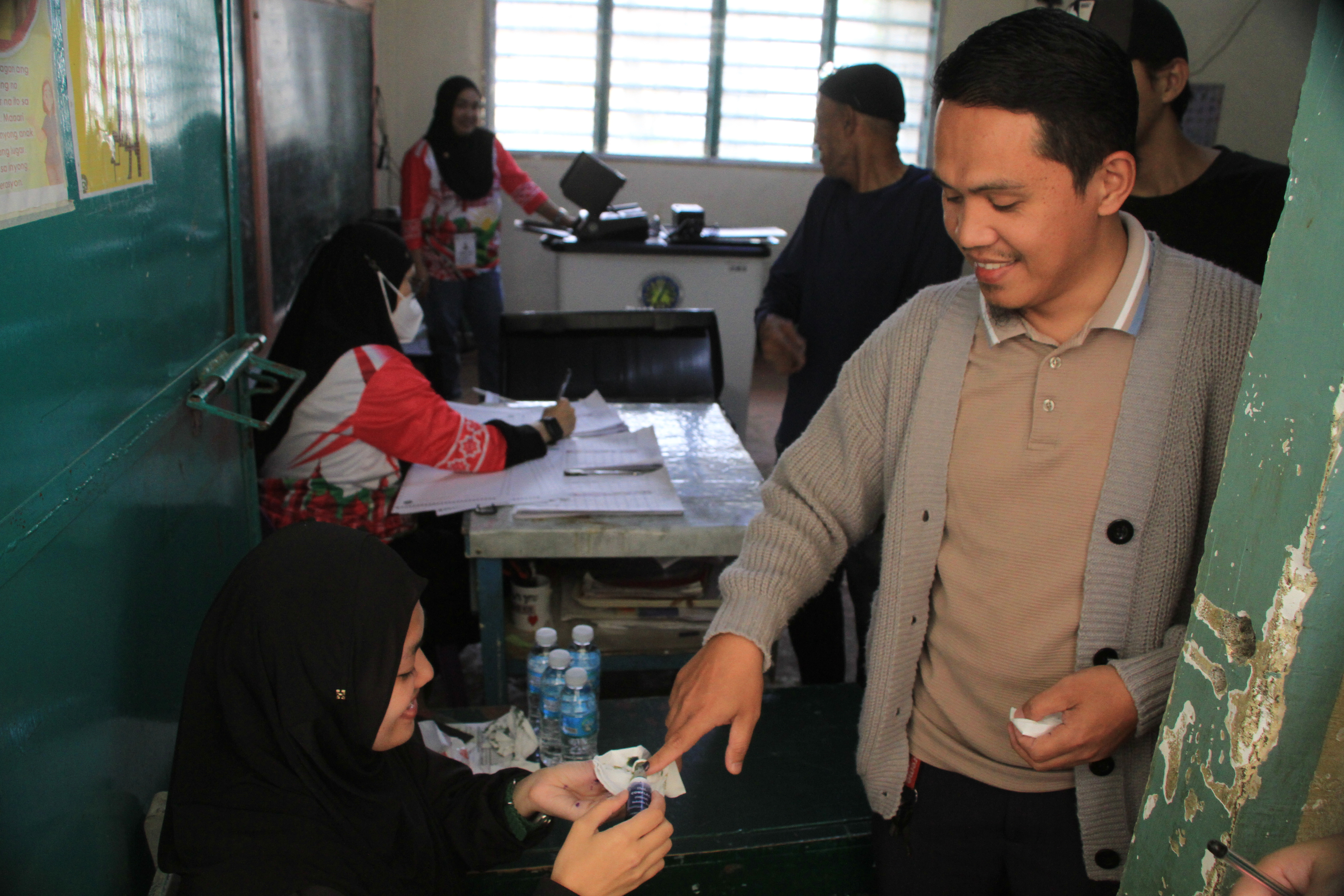 An elections worker places indelible ink on the finger of a man after voting at the Bangsamoro Autonomous Region