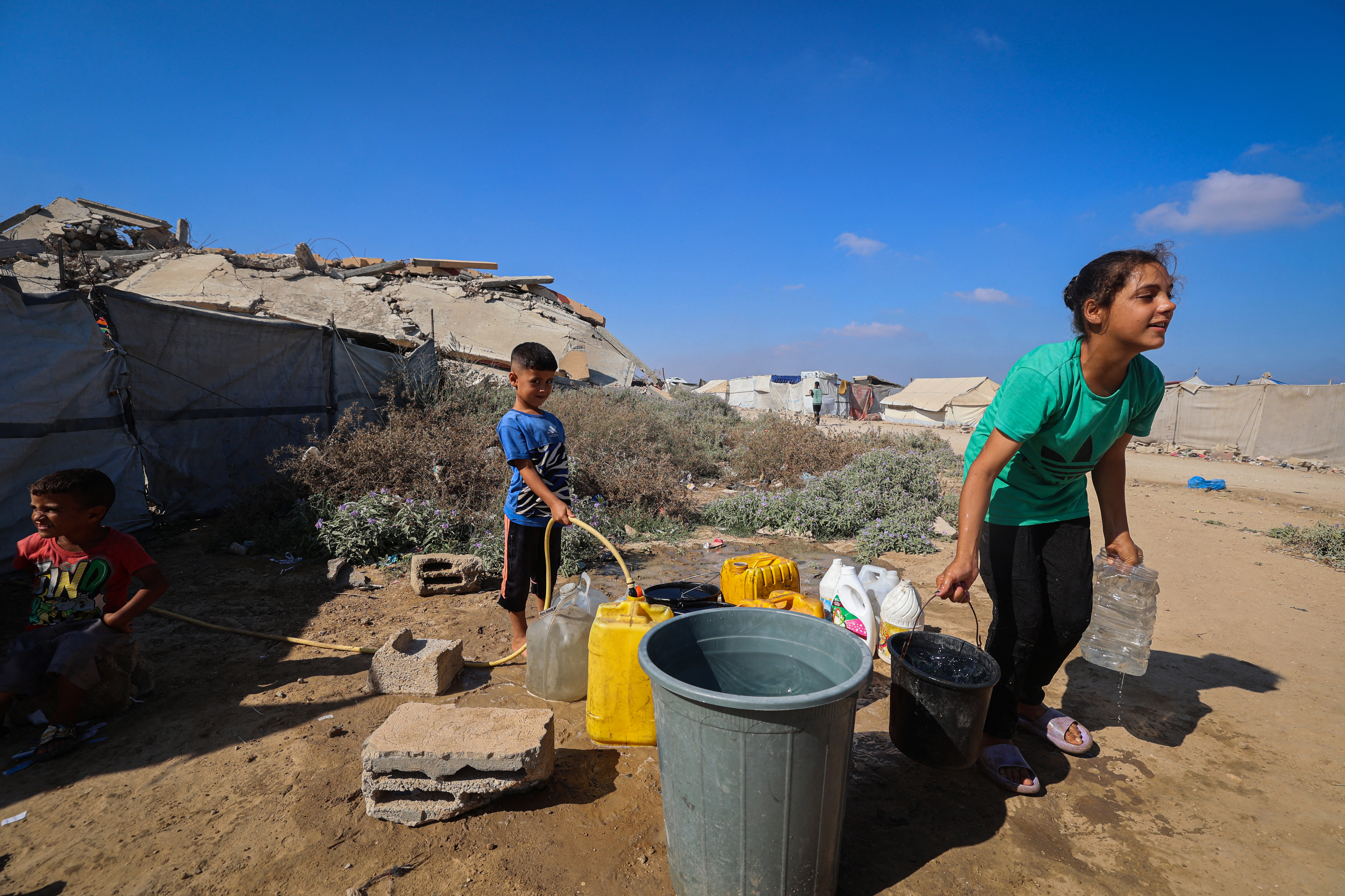 Displaced Palestinians fetch water from a cistern at a shelter camp in Bureij, central Gaza Strip on August 24, 2026.