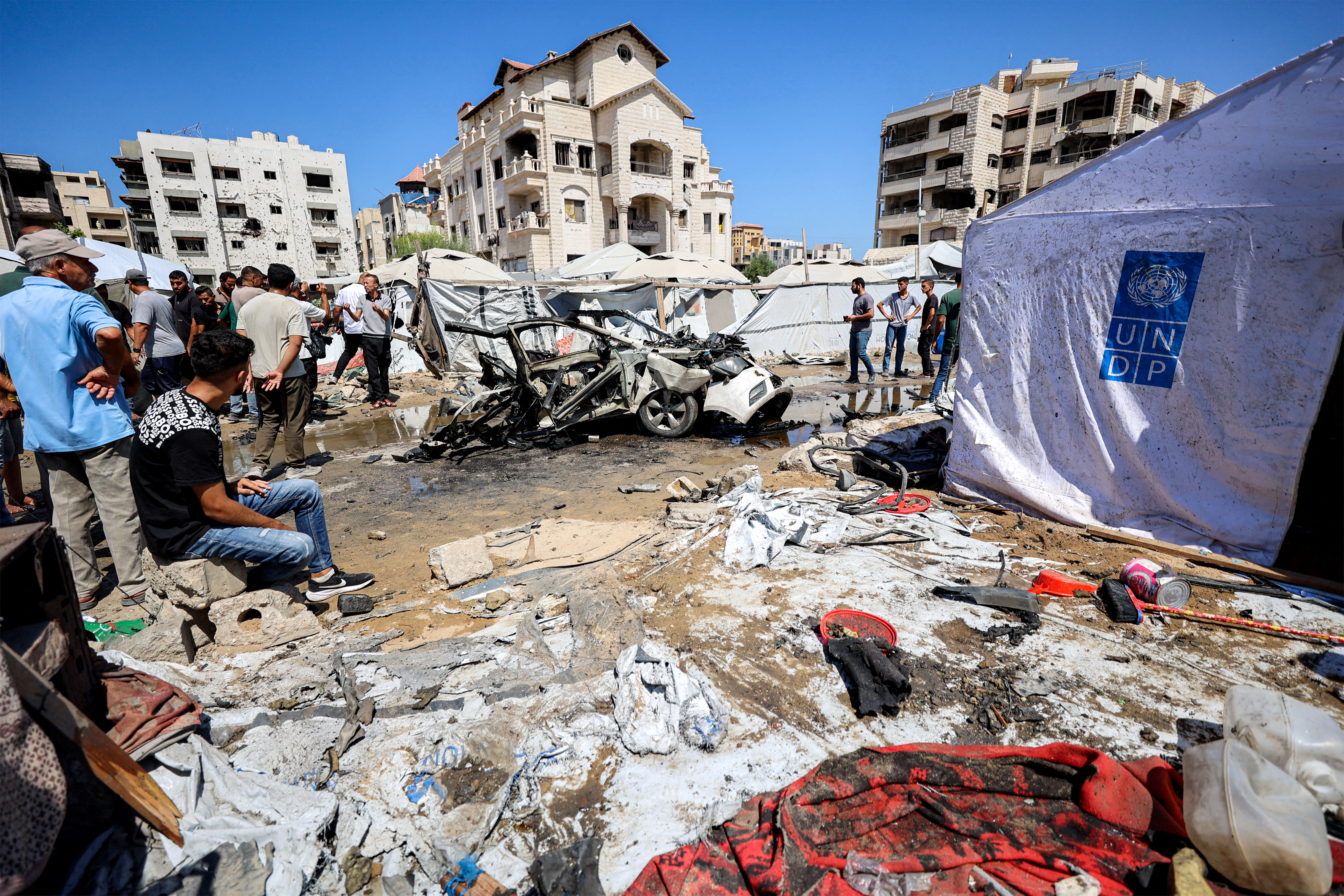 People gather near a destroyed vehicle following an Israeli strike in the Rimal neighbourhood of Gaza City on September 1, 2026.