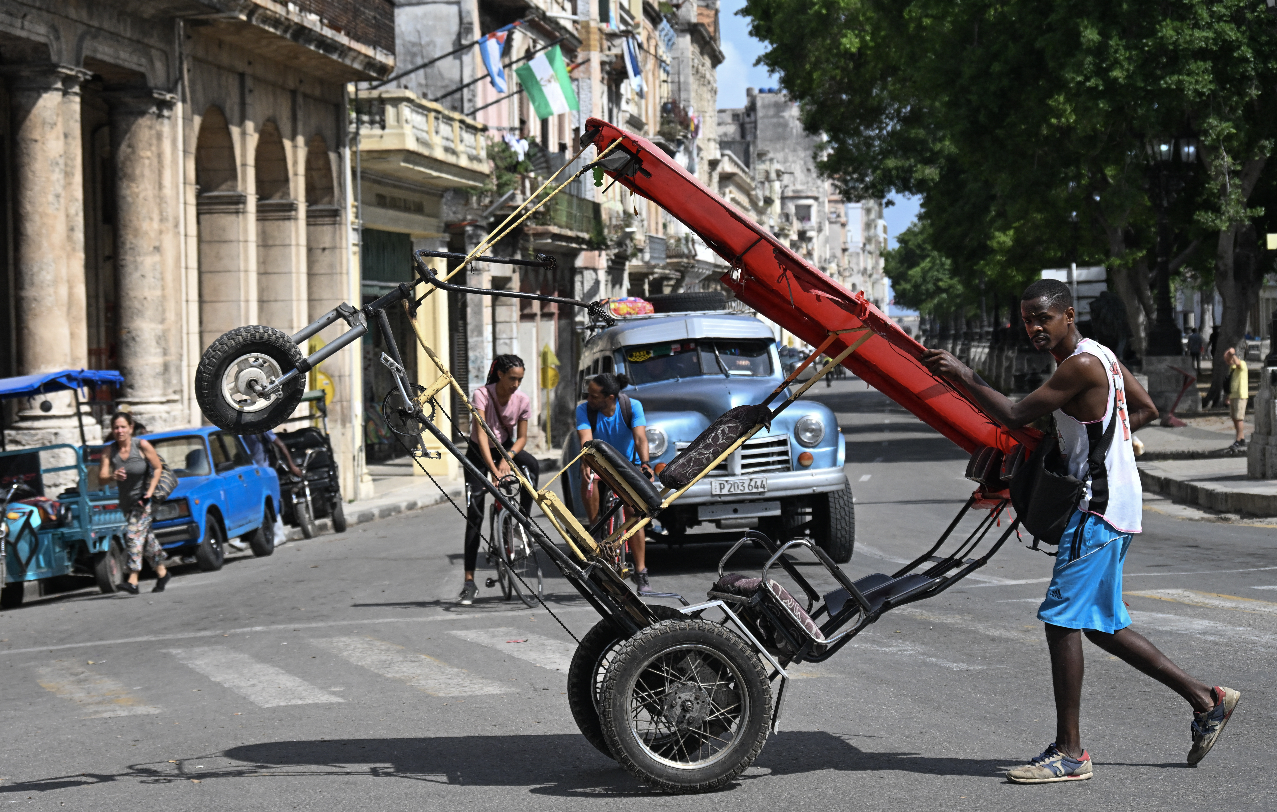 A man pushes a bicycle taxi along a street in Havana on September 7, 2026. (Photo by YAMIL LAGE / AFP)
