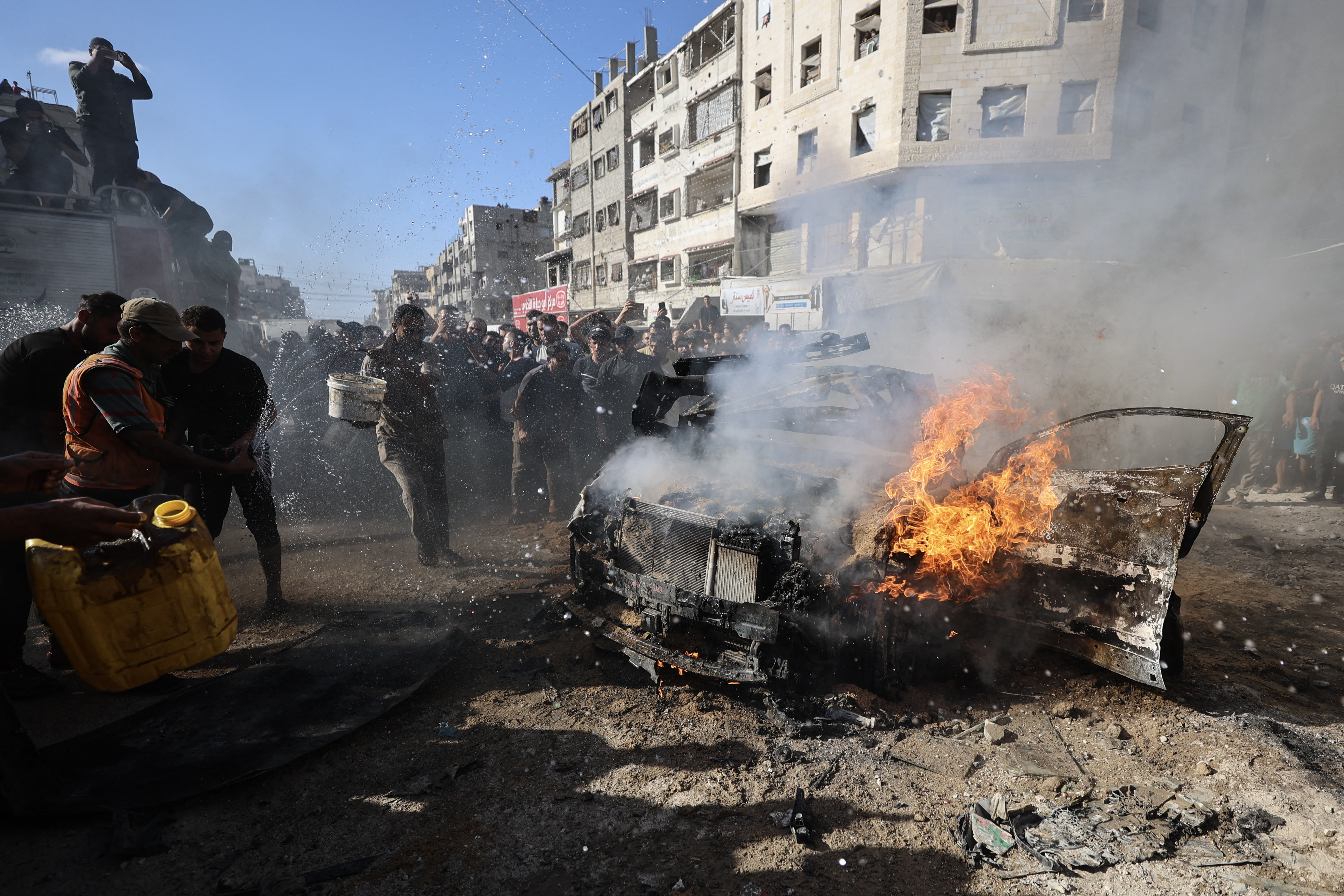 Palestinians try to put out a burning vehicle in Gaza City