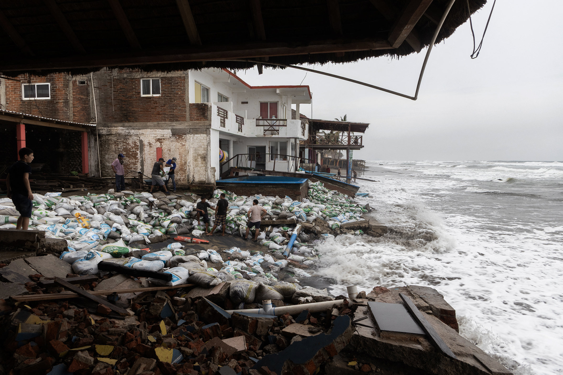 TOPSHOT - Residents place sandbags as a protective barrier against strong waves generated by Hurricane Polo at Playa Azul, in the municipality of Lazaro Cardenas, Michoacan, Mexico, on September 23, 2026.