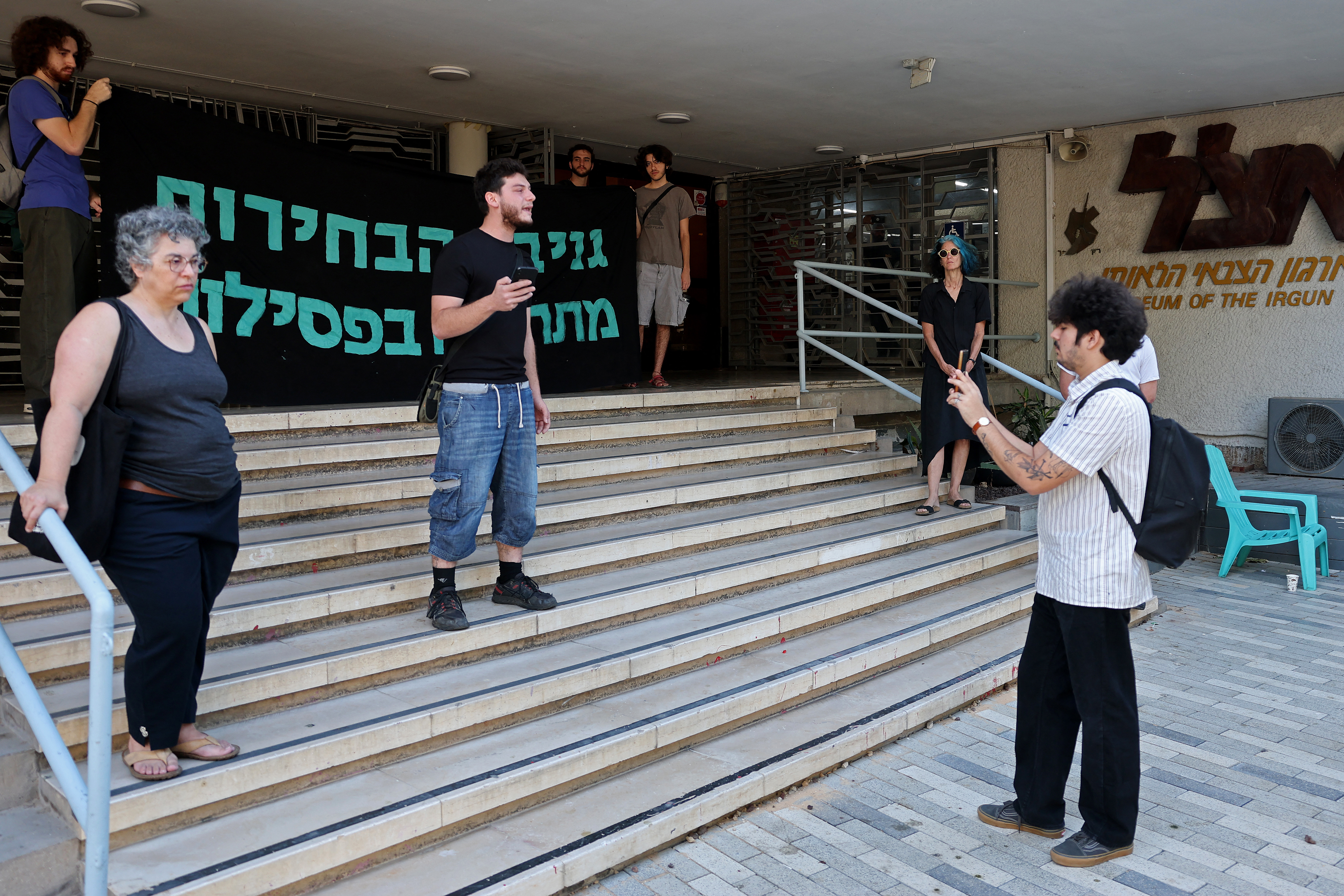 Left-wing Israeli activists hold a banner in Hebrew reading 'Election theft starts with disqualifications' as they block the entrance of Likud party headquarters during a demonstration in the coastal city of Tel Aviv on September 23, 2026, to oppose the attempt to disqualify the Joint List.