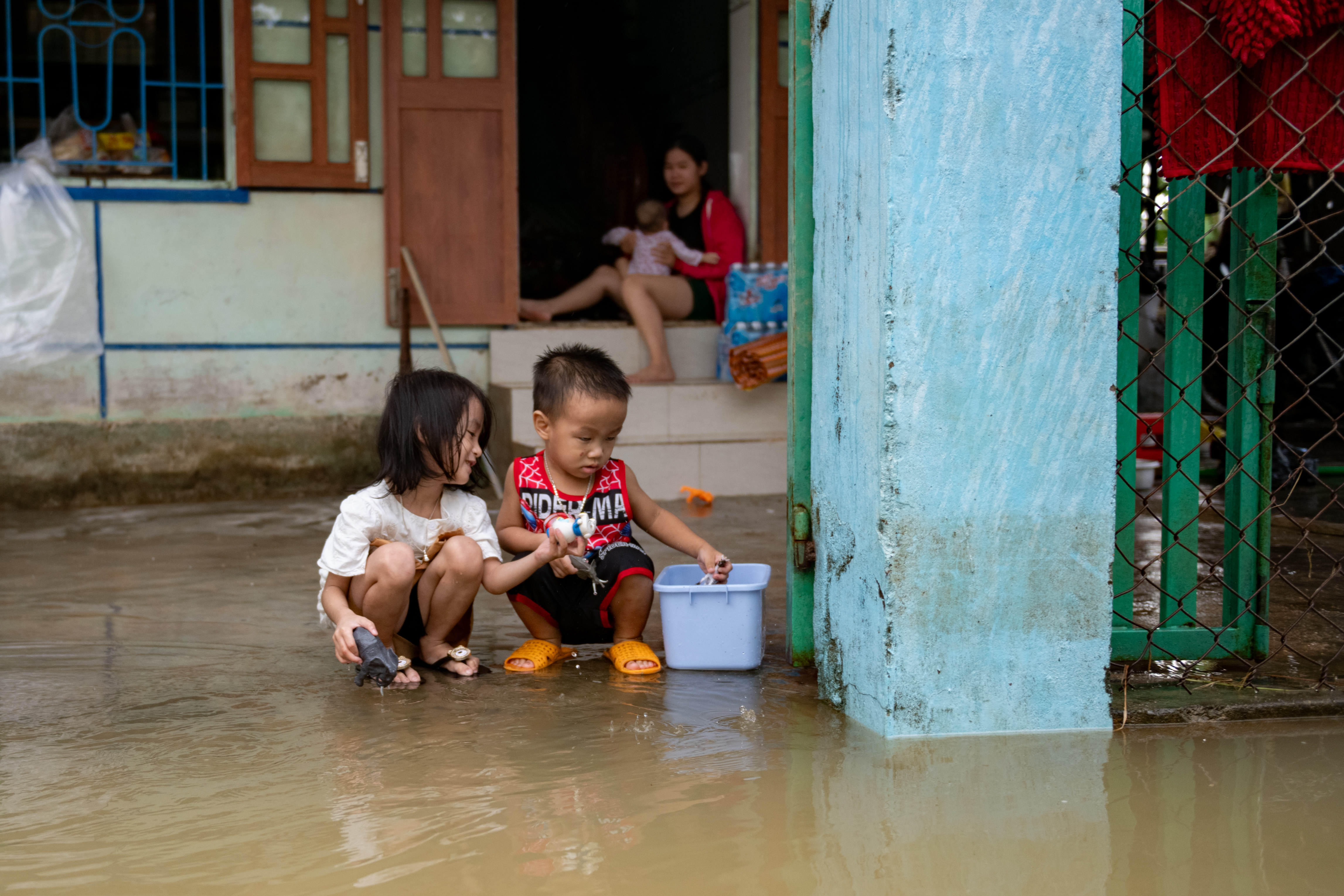 DAK LAK PROVINCE, VIETNAM - NOVEMBER 24: Children play in front of a house in Hiep Dong village, which has been isolated after days of heavy rain on November 24, 2025 in Dak Lak province, Vietnam. The central and Central Highlands regions of Vietnam have been hit by severe flooding caused by days of heavy rain. According to a nationwide report, more than 100 people are dead or missing, and the estimated damage is around $342 million. (Photo by Thanh Hue/Getty Images)