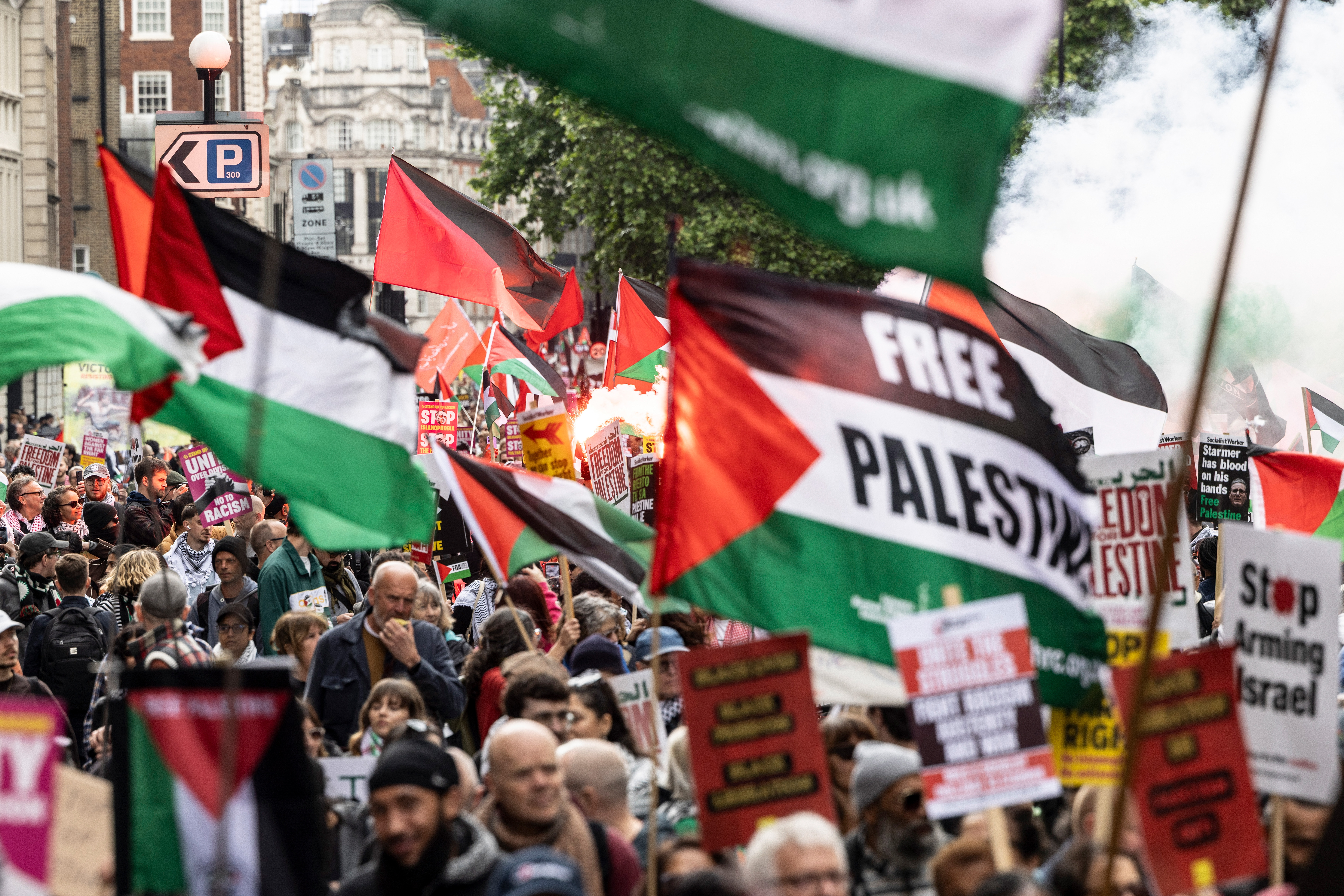 People hold up flags and light flares near Knightsbridge, London, as they take part in the 78th Nakba Anniversary March on May 16, 2026