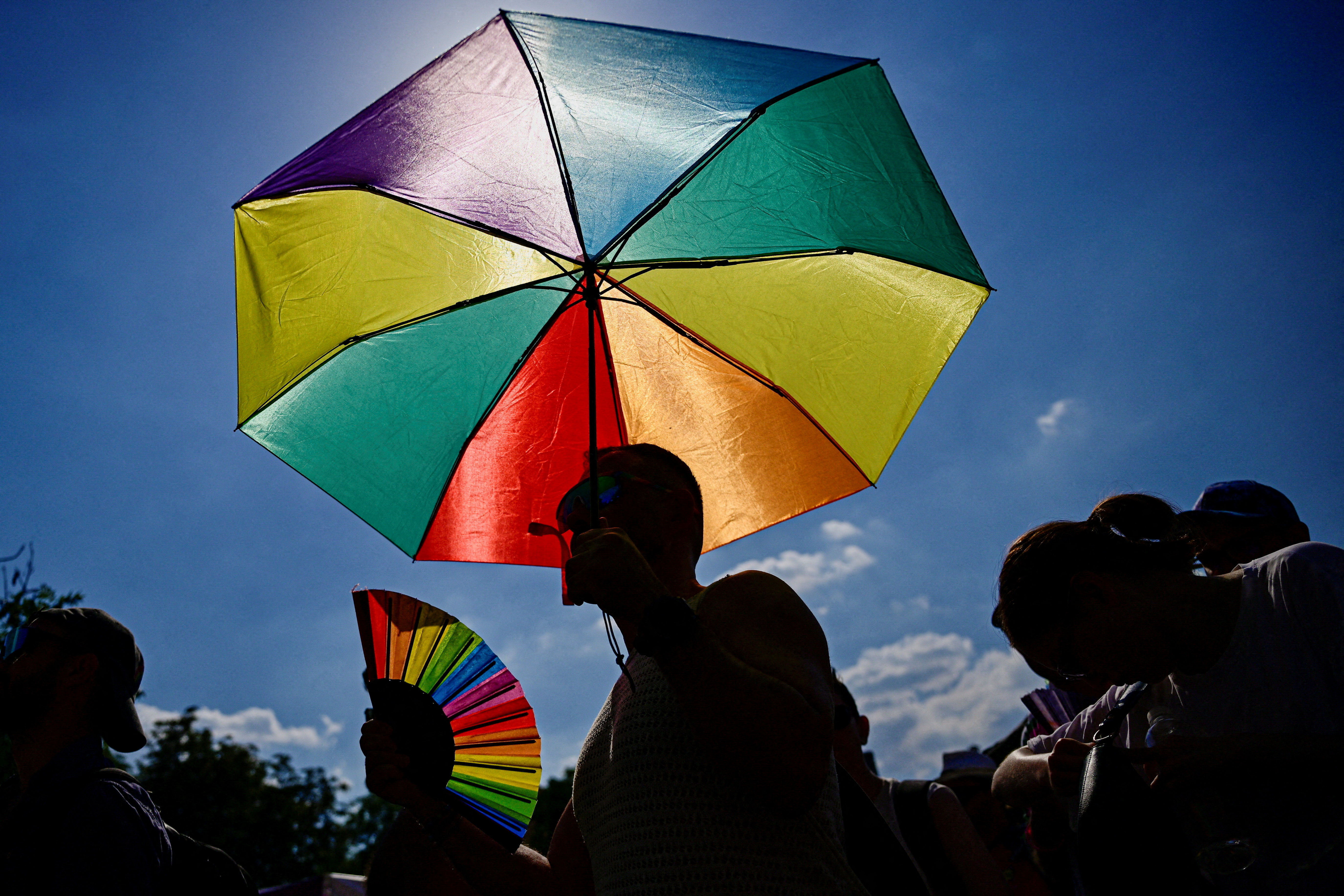An umbrella in the colors of a Pride flag as people attend the Budapest Pride march